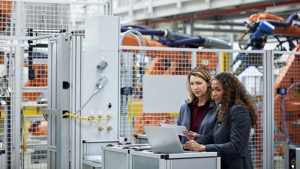 Female workers in a car factory discussing technological solutions