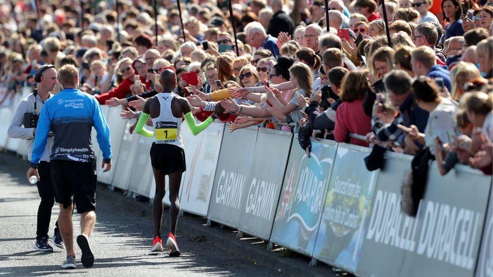 Sir Mo Farah "high fives" fans lining the side of the course