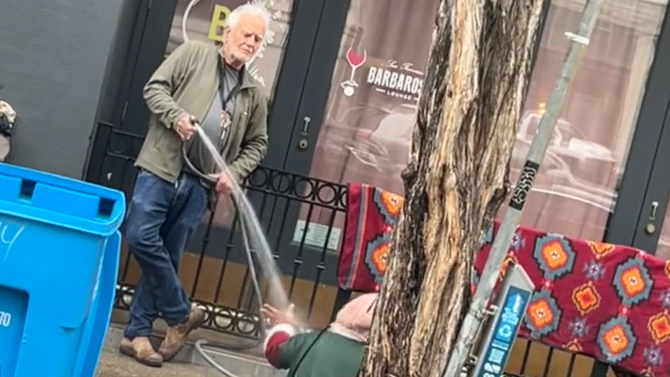 Man spraying woman with hose