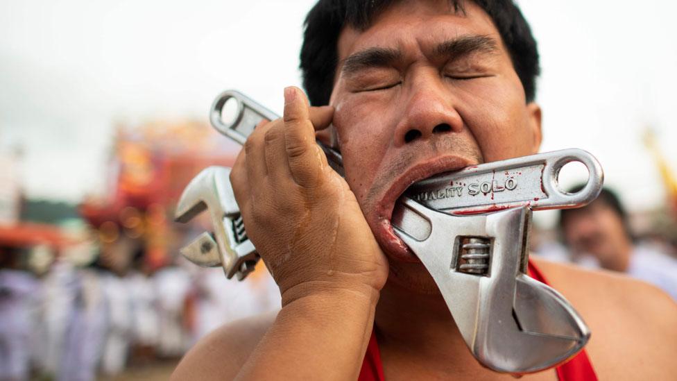 A devotee with two wrenches pierced through his cheek