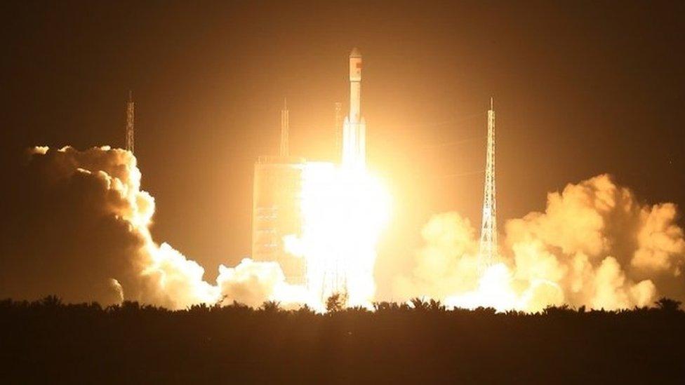 Spectators watch as a Long March 7 (CZ-7) rocket lifts off the launch pad in Wenchang in southern China"s Hainan Province