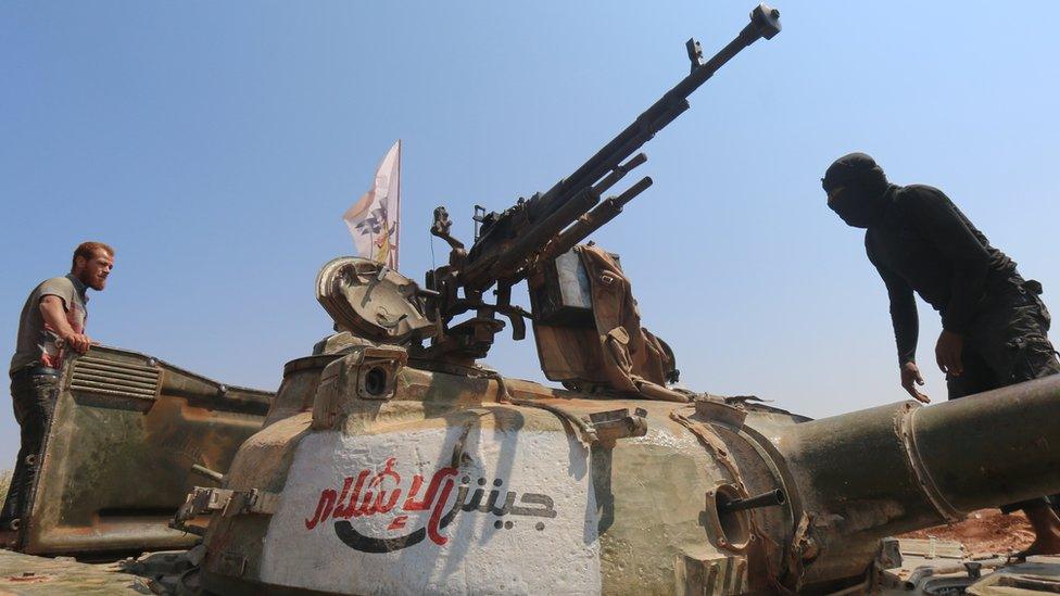 Jaish al-Islam (Army of Islam) fighters stand on a tank near the frontline in the al-Zahra area, on the northwestern outskirts of Aleppo in 2015