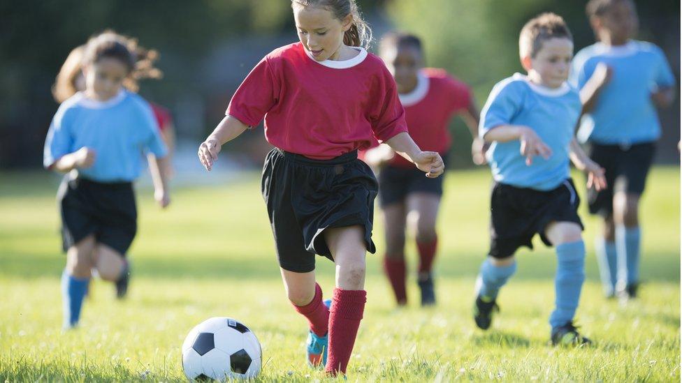 Girls and boys playing football