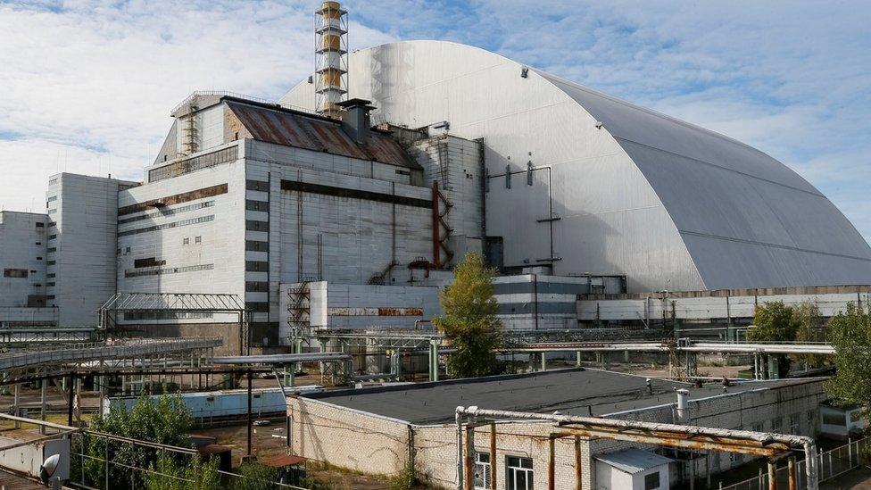 A new Safe Confinement arch covers the damaged fourth reactor of the Chernobyl nuclear power plant near a newly built solar power plant in Chernobyl