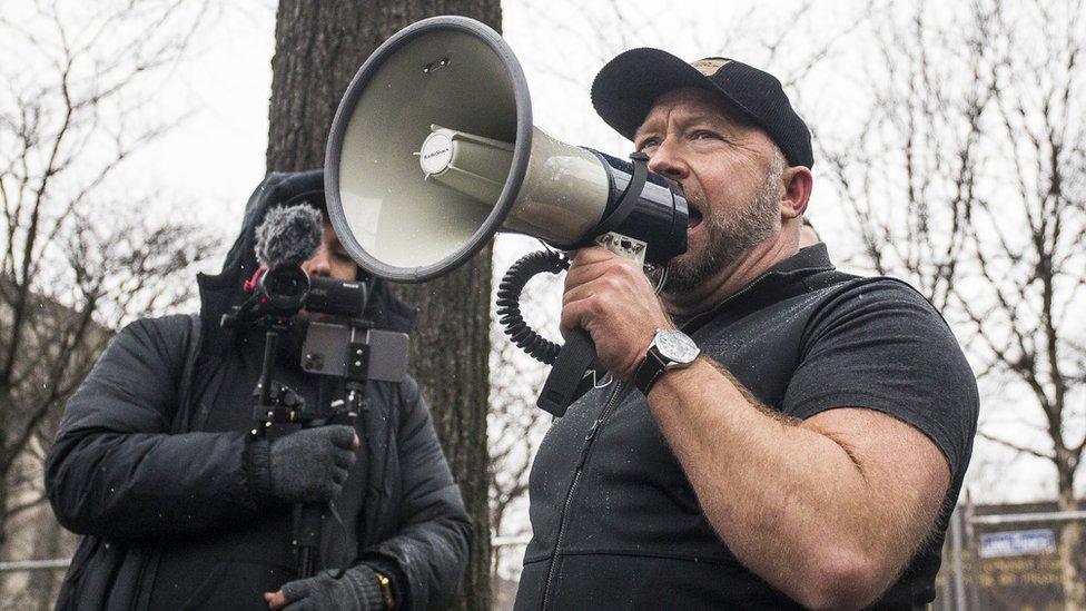 Alex Jones holds a megaphone while being filmed