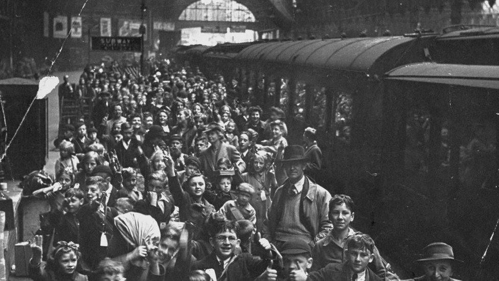 Child evacuees queuing at a train station waiting to board trains so they can leave London.