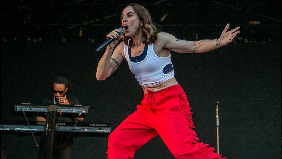 Melanie C performing onstage wearing a white vest and red trousers at Victorious 2021