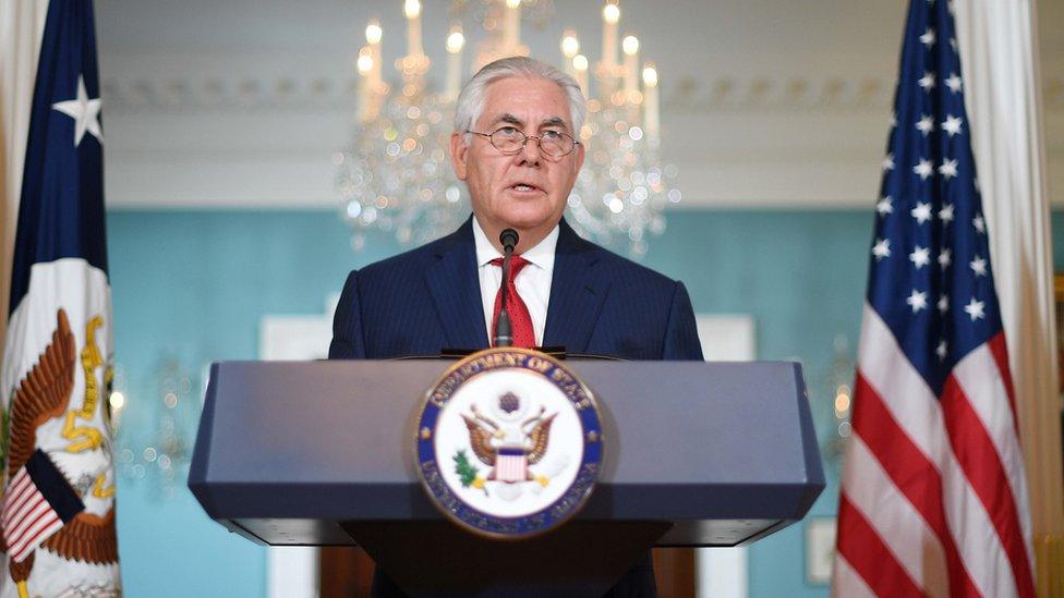 Rex Tillerson speaks from a podium, flanked by the state department and American flags