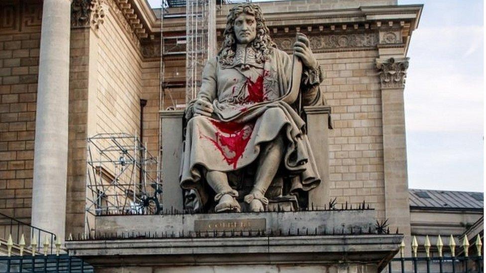 Authorities stand around the statue of Jean-Baptiste Colbert, vandalised by an activist