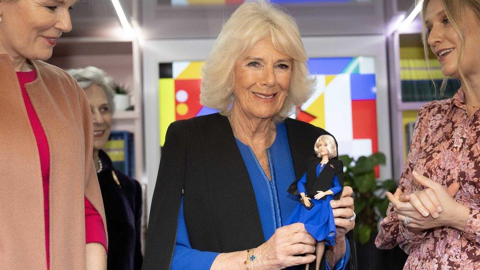 Queen Camilla holding the Barbie doll of herself