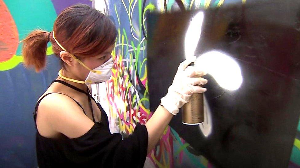 Woman graffitis a Hong Kong flag