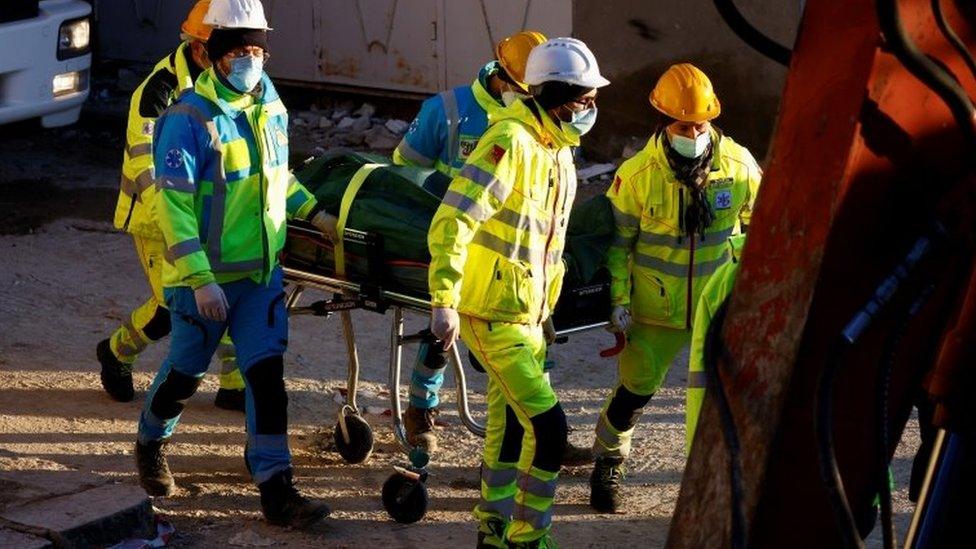 Rescuers carry a body on a stretcher on Monday