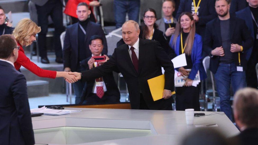 Russian President Vladimir Putin enters the hall during his combined call-in-show and annual news conference