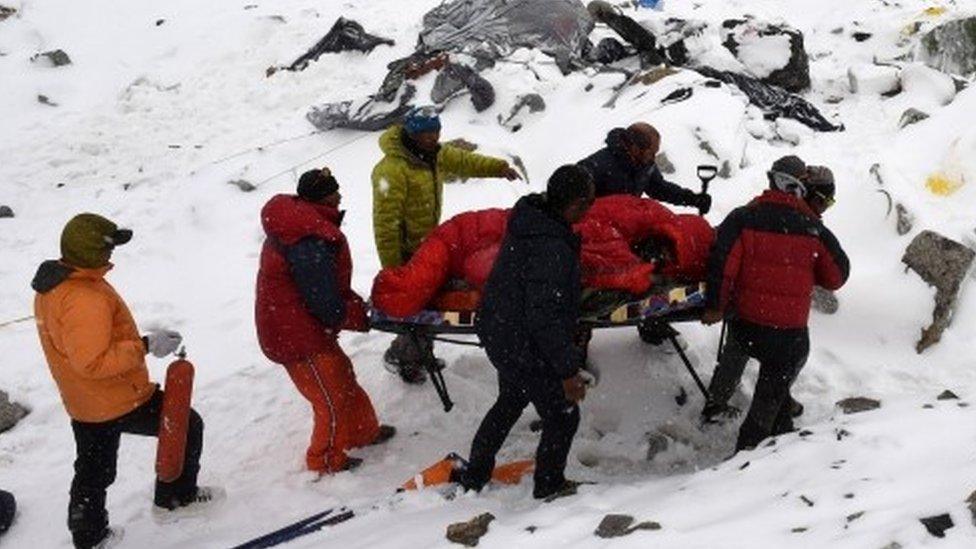 Rescuers use a makeshift stretcher to carry an injured person after an avalanche triggered by an earthquake flattened parts of Everest Base Camp(25 April 2015)