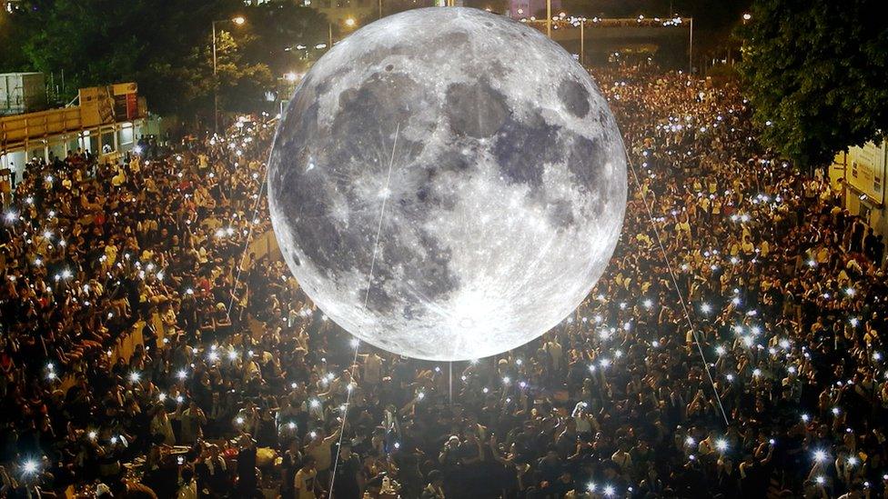 Moon balloon superimposed above a crowd