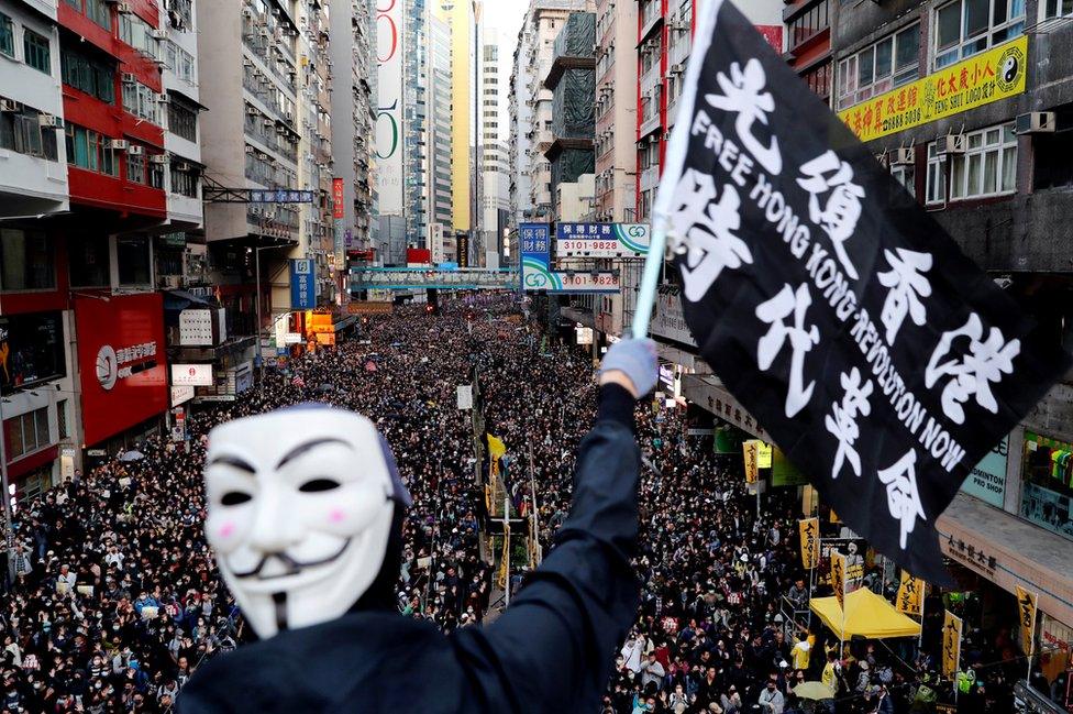 A protester wearing a Guy Fawkes mask waves a flag during a Human Rights Day march, organised by the Civil Human Rights Front, in Hong Kong, 8 December 2019.