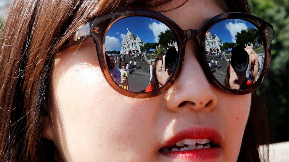 Montmartre's Sacre Coeur church is reflected in the sunglasses of a Korean tourist in Paris, France, 20 August