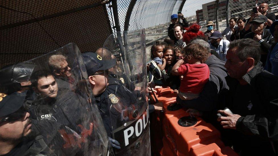 Police face migrants at the US-Mexico border on Sunday