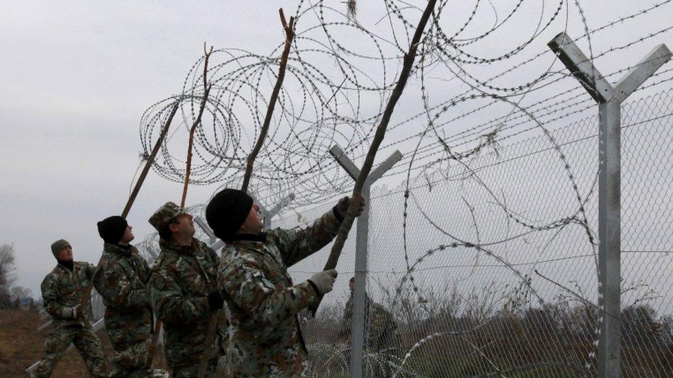 Macedonian Army engineers set a razor wire atop a fence on the border line between Macedonia and Greece