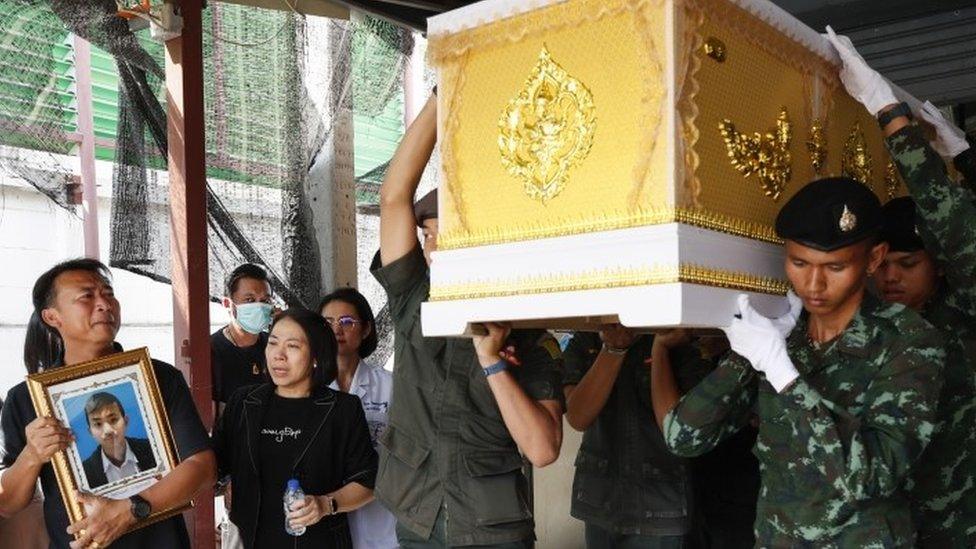 Thai father holds a portrait of his 13-year-old son, who was shot dead