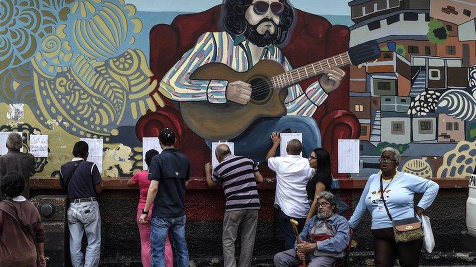 People look for their names on electoral rolls before voting in the municipal elections in Caracas on December 10, 2017.