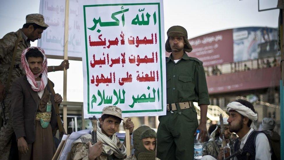 Armed Houthi rebels in Sanaa carry a poster saying: "God is great. Death to America. Death to Israel. A curse on the Jews. Victory to Islam." (23 January 2015)