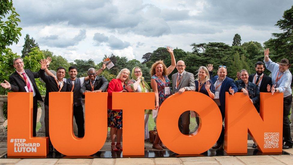 People by an orange Luton sign