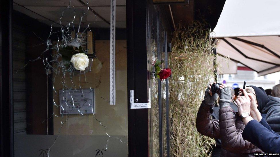 People take photos of flowers in shattered windows