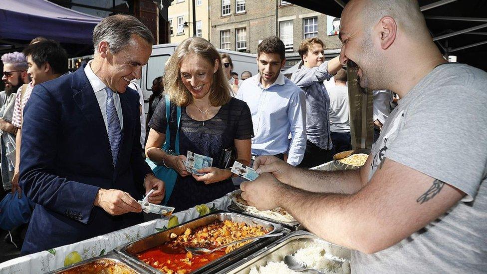 Bank of England governor Mark Carney tests a new polymer five pound note as he buys lunch at Whitecross Street Market on September 13, 2016