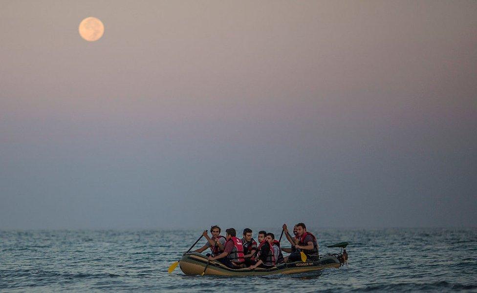 Migrant families arrive in an inflatable dinghy on the beach at Kos, Greece in August 2015