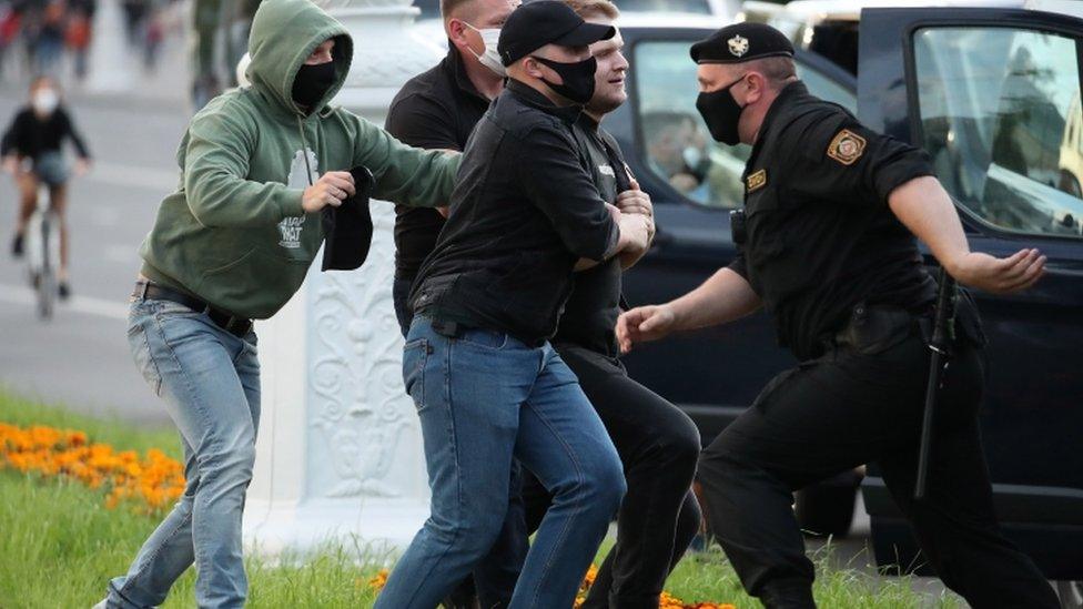 Police officers wearing protective face masks detain a protester during a rally in Minsk, Belarus