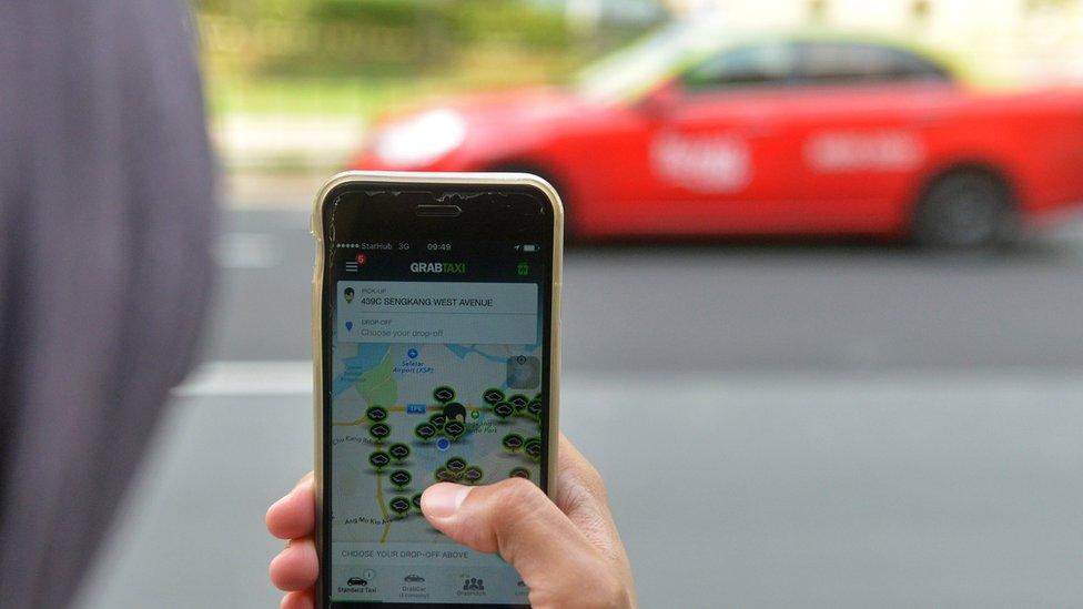 Woman looks at a ride-hailing app on her phone