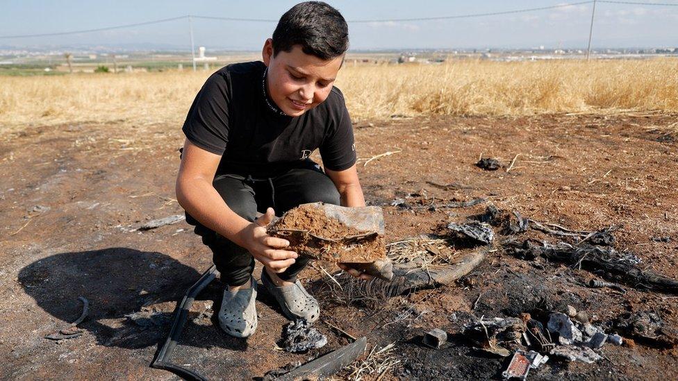 A boy looks at a metal fragment following an Israeli drone strike in the northern West Bank that killed three Palestinian militants (22 June 2023)