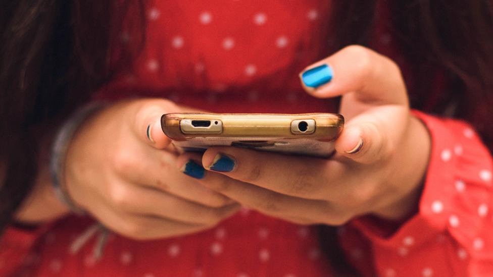 Stock image of a teenager holding a phone