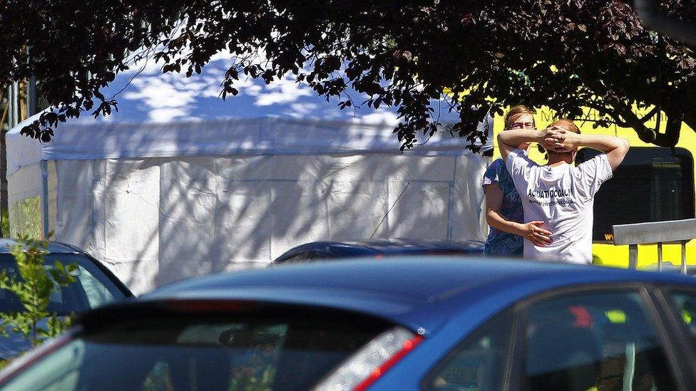 Two people watching with tent in background