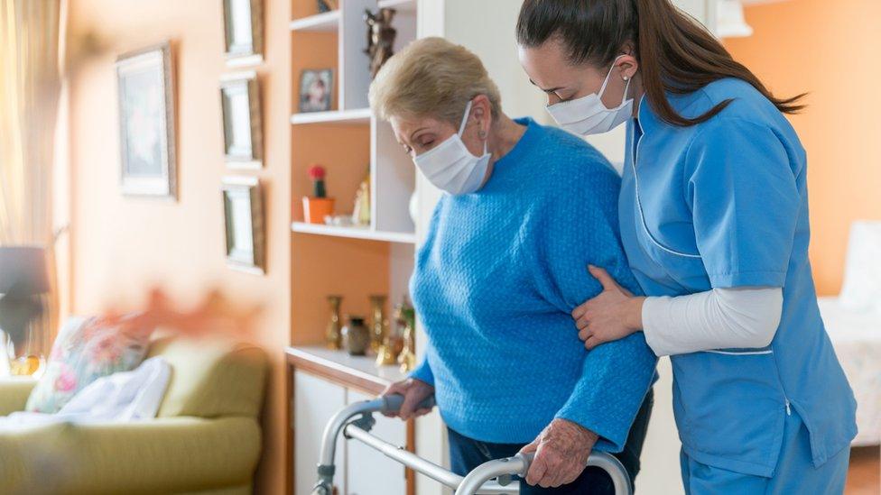 Social care worker assisting elderly client (stock photo)