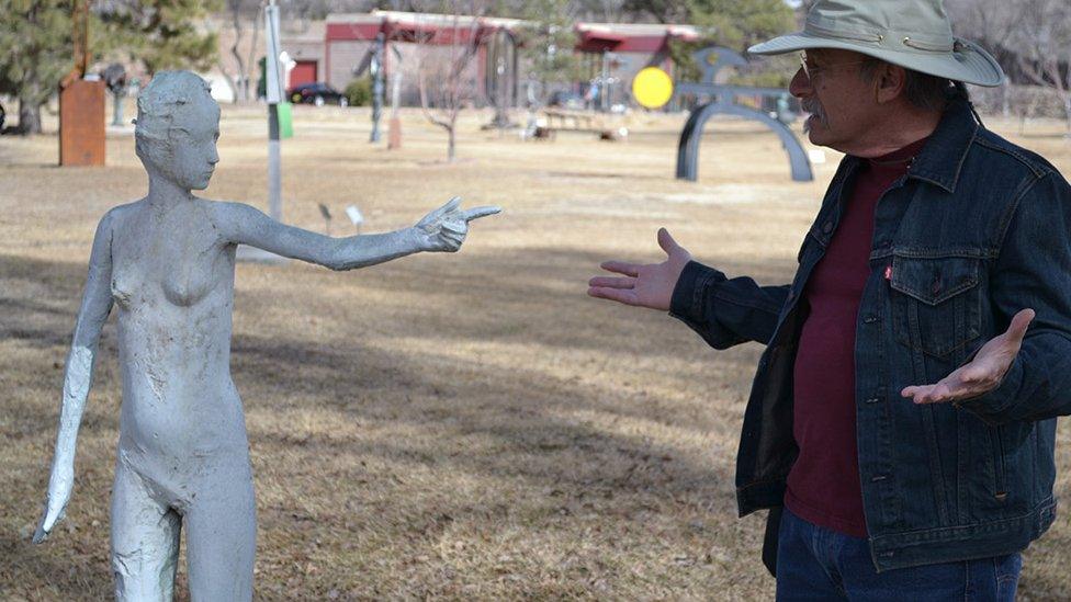 A sculpture pointing at a man