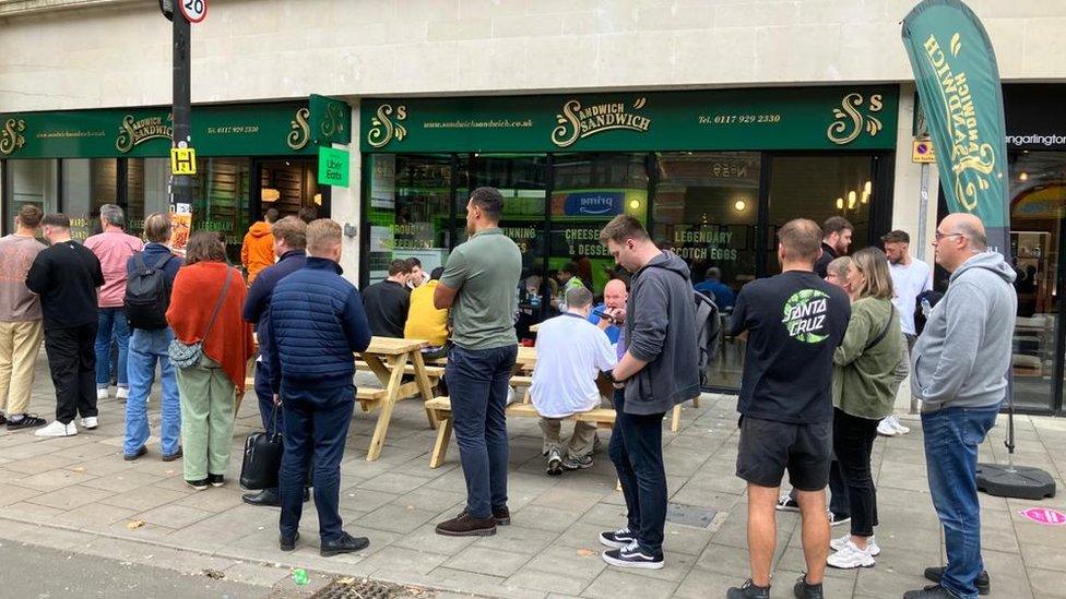 A queue out the door of a sandwich company