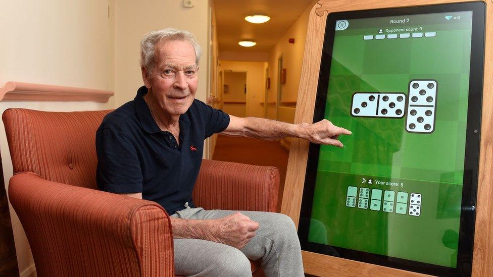 Down Hall resident Stanley playing dominoes on a giant tablet.