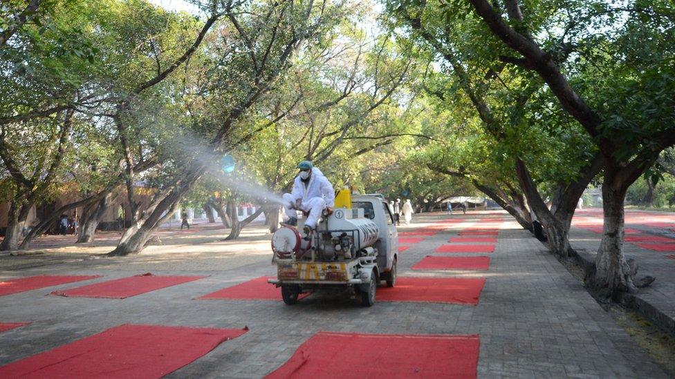 Workers disinfect the area where muslims offer the Eid al Fitr prayer in Peshawar