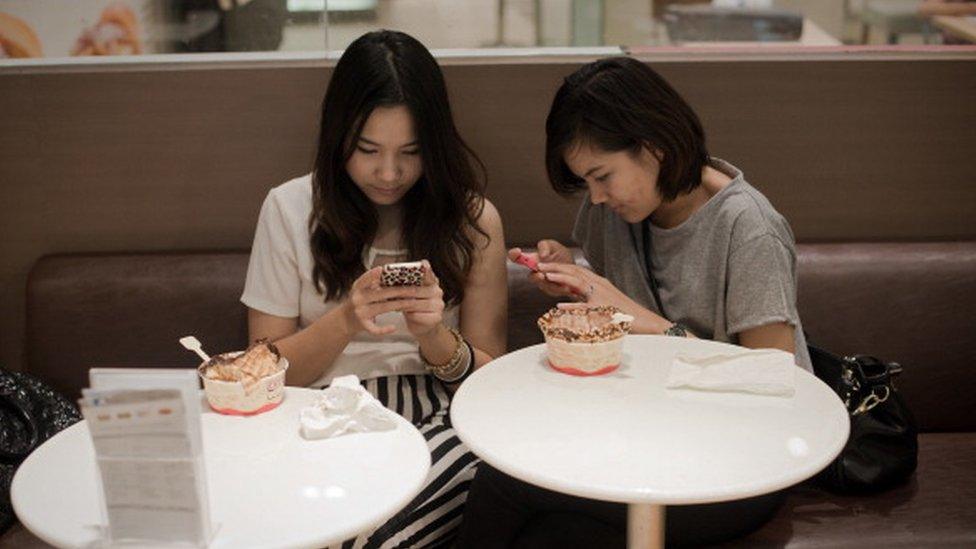 Two girls chatting on their phones