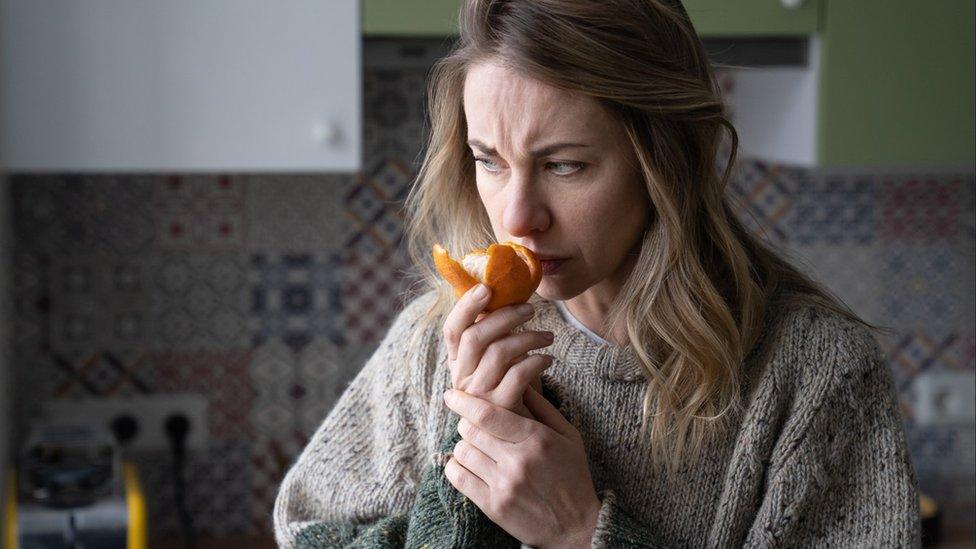 Women struggles to smell an orange