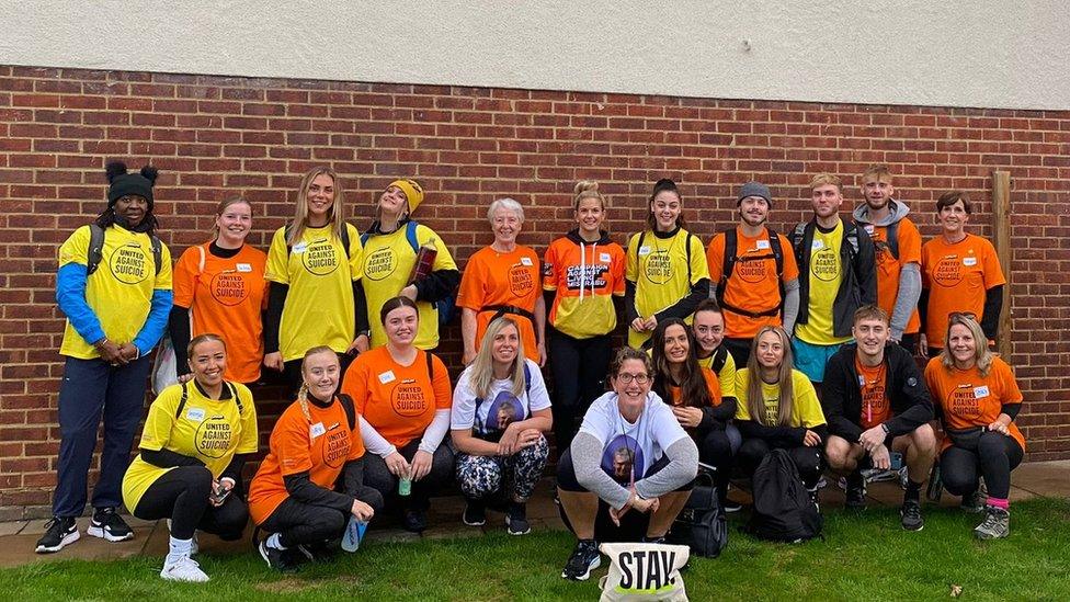 A photo of a group of walk attendees and campaigners surrounding Tracey Boxall (crouching down)