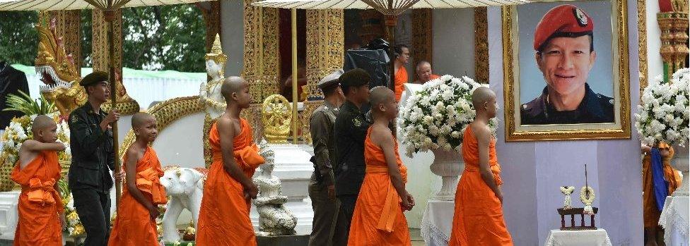 The rescued Thai boys and members of the "Wild Boars" football team ordained as novice Buddhist monks walk in procession by the portrait of former Thai Navy SEAL diver Saman Gunan