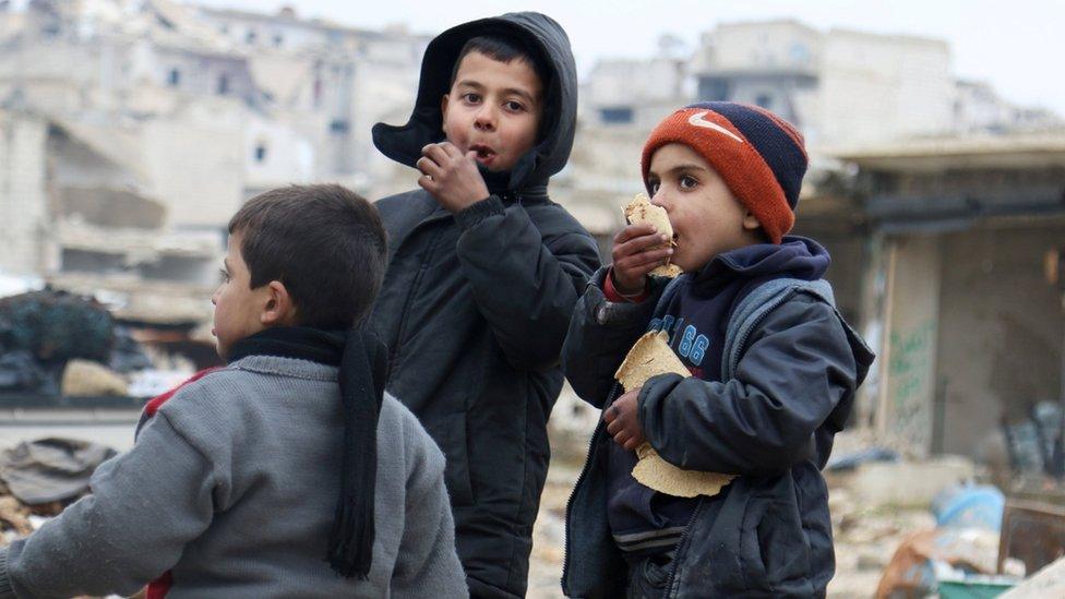 Boys eat bread as they wait to be evacuated from a rebel-held sector of eastern Aleppo, Syria