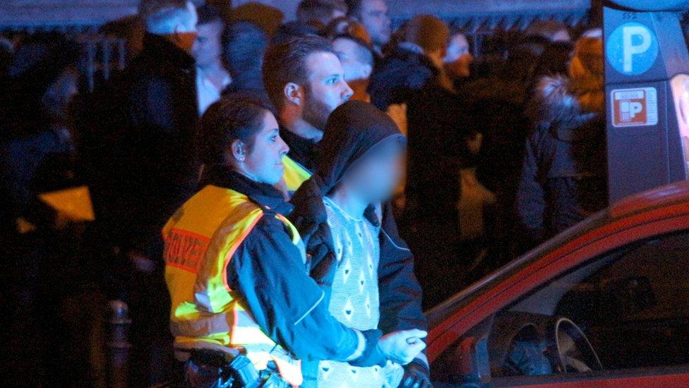 A policewoman holds a young man on 31 December at Cologne station