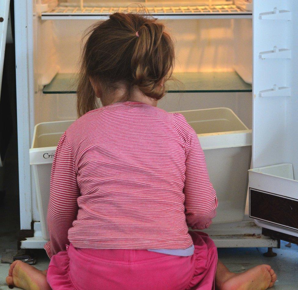 child beside empty fridge