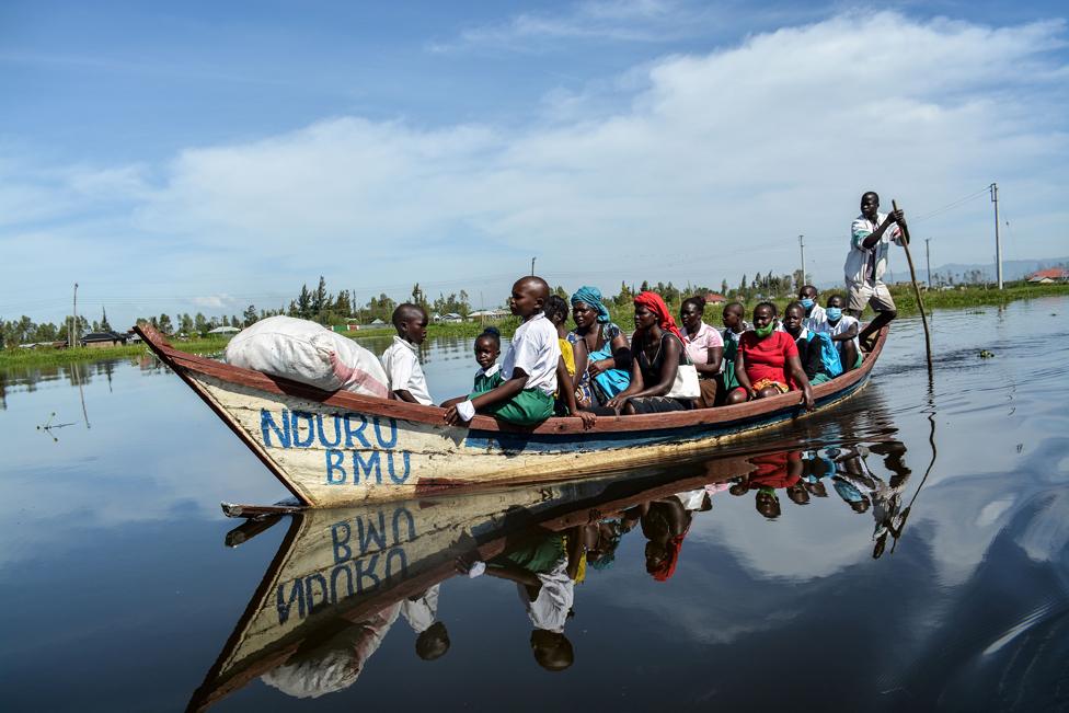 Parents and students ride on a boat to their school in a flooded water area caused by the overflow of Lake Victoria in Kisumu, Kenya on 4 January 2021