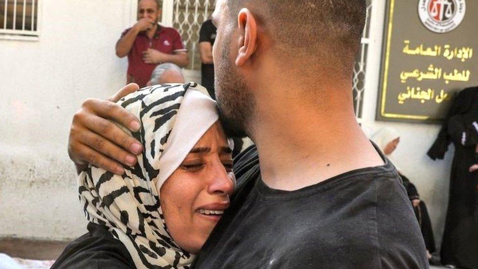 A man comforts a woman mourning outside the morgue of al-Shifa hospital in Gaza City on October 12, 2023