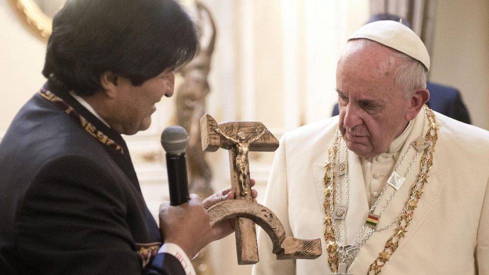 Pope Francis is presented with a gift of a hammer and sickle-shaped crucifx